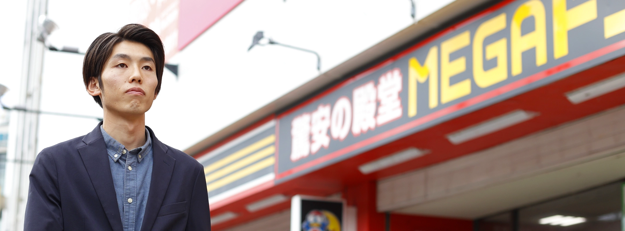 店舗の外で正面を見つめるN.H.さん