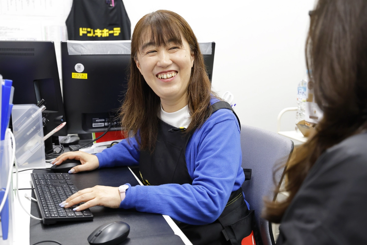 パソコン作業をしながら笑顔でメイトと話すH.T.さん